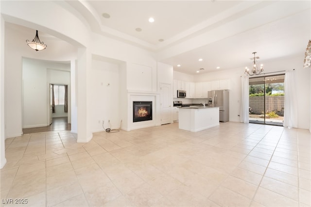 9025 Loggers Mill Ave, Las Vegas, NV 89143 - unfurnished living room featuring light tile patterned flooring, a chandelier, a glass covered fireplace, recessed lighting, and arched walkways