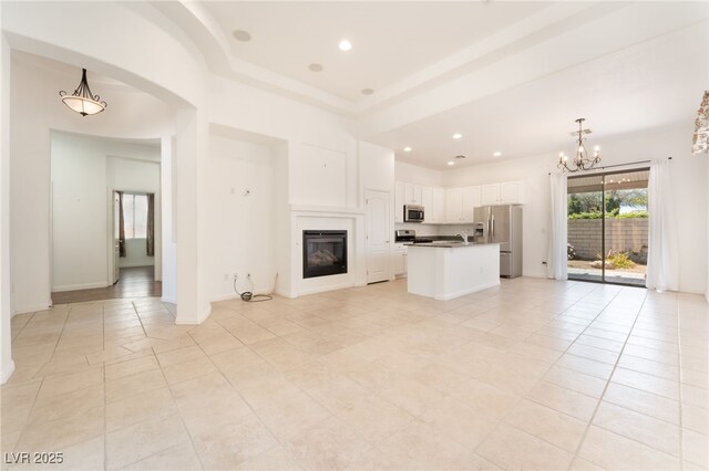 9025 Loggers Mill Ave, Las Vegas, NV 89143 - unfurnished living room featuring light tile patterned floors, a chandelier, a glass covered fireplace, recessed lighting, and arched walkways