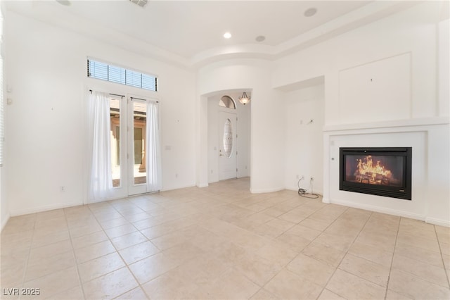 9025 Loggers Mill Ave, Las Vegas, NV 89143 - unfurnished living room featuring light tile patterned floors, a glass covered fireplace, a towering ceiling, baseboards, and recessed lighting