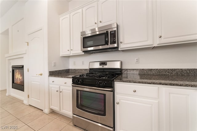 9025 Loggers Mill Ave, Las Vegas, NV 89143 - kitchen with appliances with stainless steel finishes, white cabinets, light tile patterned flooring, and dark stone countertops