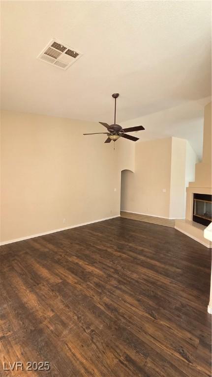 6113 Desert Haven Rd, Las Vegas, NV 89130 - unfurnished living room with dark wood-style flooring, a ceiling fan, a glass covered fireplace, and baseboards
