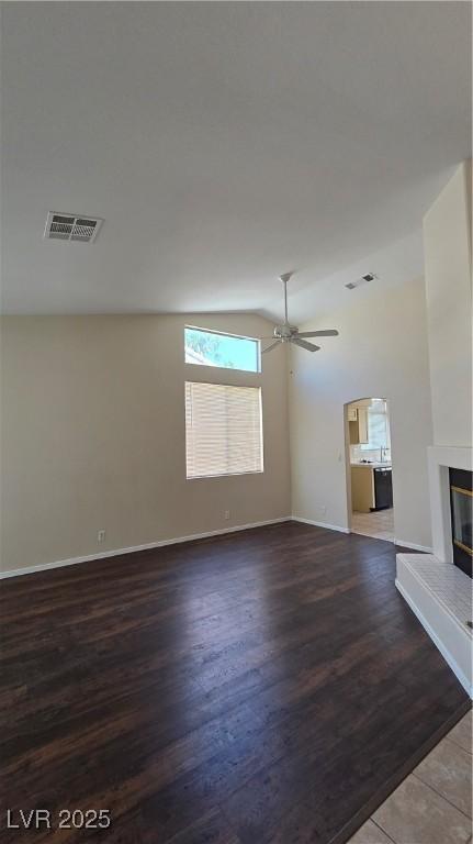 6113 Desert Haven Rd, Las Vegas, NV 89130 - unfurnished living room featuring wood finished floors, ceiling fan, lofted ceiling, a glass covered fireplace, and baseboards