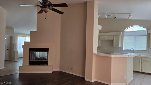 6113 Desert Haven Rd, Las Vegas, NV 89130 - unfurnished living room featuring healthy amount of natural light, ceiling fan, a multi sided fireplace, and light wood-style floors