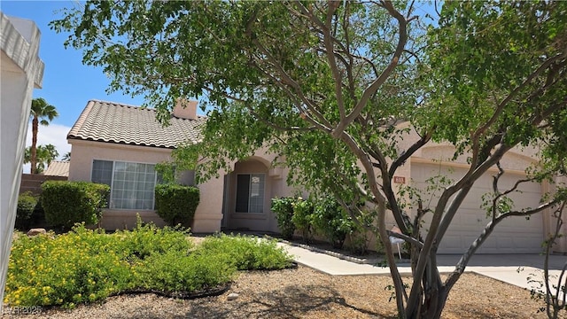 6113 Desert Haven Rd, Las Vegas, NV 89130 - view of property hidden behind natural elements with a tiled roof, stucco siding, concrete driveway, a chimney, and a garage