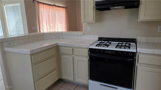 6113 Desert Haven Rd, Las Vegas, NV 89130 - kitchen with range with gas cooktop, under cabinet range hood, a peninsula, light tile patterned floors, and tile countertops