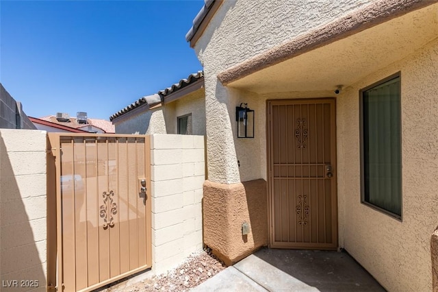 1905 Eskam St, Las Vegas, NV 89156 - entrance to property featuring a gate, stucco siding, a security system, and a tiled roof