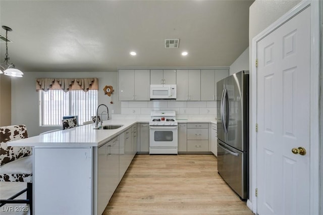 1905 Eskam St, Las Vegas, NV 89156 - kitchen with white appliances, a sink, a peninsula, light wood-type flooring, and tasteful backsplash