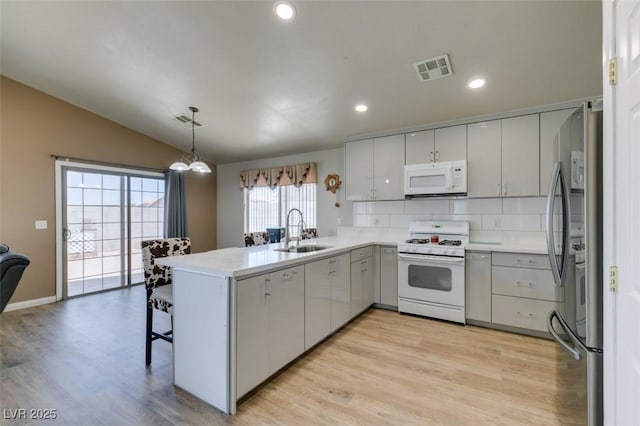 1905 Eskam St, Las Vegas, NV 89156 - kitchen featuring white appliances, a sink, vaulted ceiling, a peninsula, and light wood-style floors