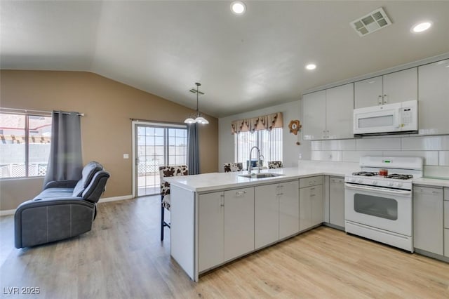 1905 Eskam St, Las Vegas, NV 89156 - kitchen featuring white appliances, a sink, a peninsula, vaulted ceiling, and light wood finished floors