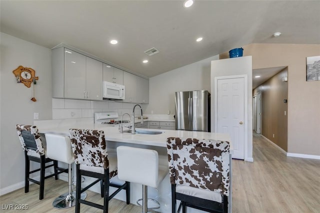 1905 Eskam St, Las Vegas, NV 89156 - kitchen with freestanding refrigerator, white microwave, a sink, a peninsula, and light wood-type flooring