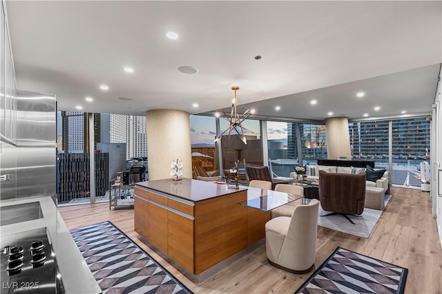 3726 Las Vegas Blvd Unit 606, Las Vegas, NV 89158 - kitchen featuring light wood-type flooring, black electric cooktop, a kitchen island, decorative columns, and recessed lighting