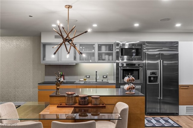 3726 Las Vegas Blvd Unit 606, Las Vegas, NV 89158 - kitchen with appliances with stainless steel finishes, a sink, a chandelier, light wood finished floors, and dark countertops