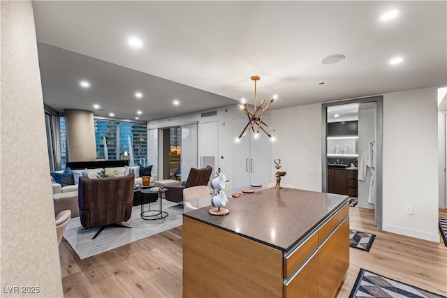 3726 Las Vegas Blvd Unit 606, Las Vegas, NV 89158 - kitchen with dark countertops, light wood-type flooring, a kitchen island, recessed lighting, and a chandelier