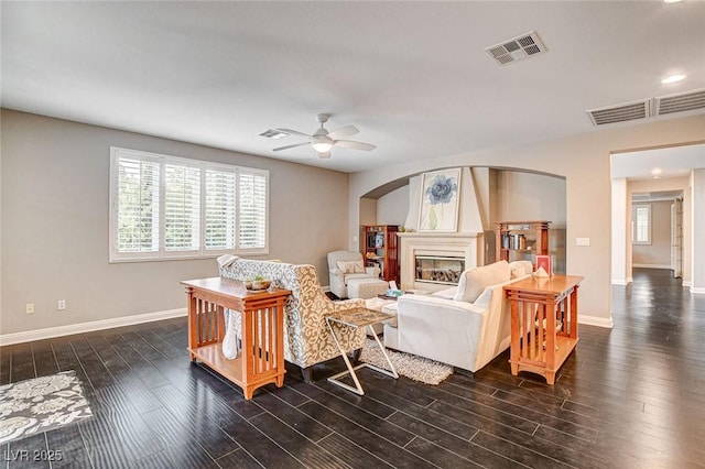 10671 Capesthorne Way, Las Vegas, NV 89135 - living area featuring baseboards, a glass covered fireplace, arched walkways, a ceiling fan, and dark wood-style flooring