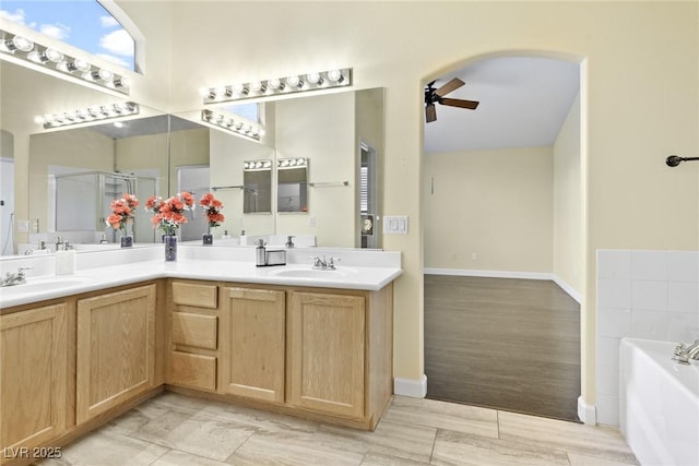 8221 Stoneheather Ct, Las Vegas, NV 89117 - bathroom with ceiling fan, double vanity, a bath, a shower stall, and baseboards