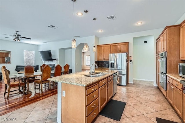 313 Glenridding St, Las Vegas, NV 89183 - kitchen featuring stainless steel appliances, tasteful backsplash, light tile patterned floors, an island with sink, and light stone counters