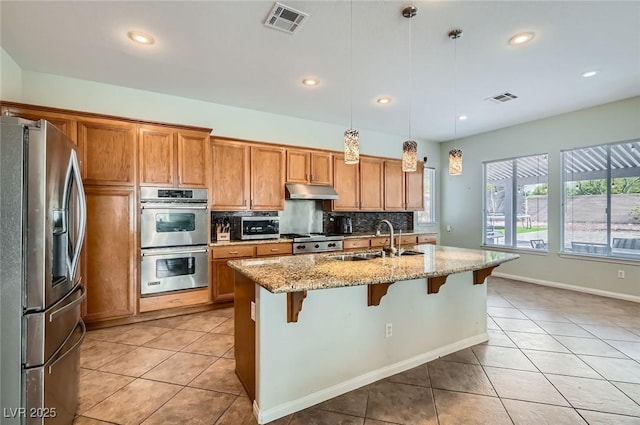 313 Glenridding St, Las Vegas, NV 89183 - kitchen featuring stainless steel appliances, light tile patterned flooring, brown cabinetry, a breakfast bar area, and recessed lighting