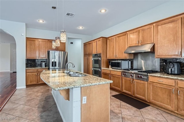 313 Glenridding St, Las Vegas, NV 89183 - kitchen featuring appliances with stainless steel finishes, under cabinet range hood, arched walkways, backsplash, and light stone countertops