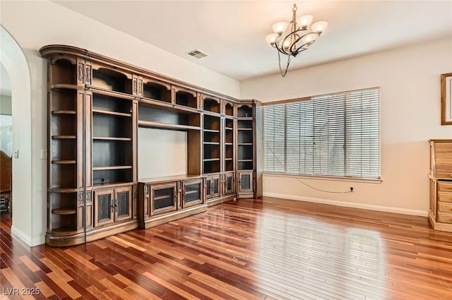 313 Glenridding St, Las Vegas, NV 89183 - unfurnished living room featuring arched walkways, hardwood / wood-style floors, and a chandelier