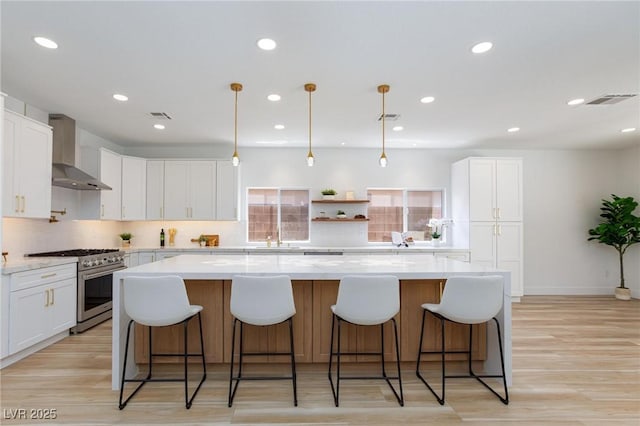 81 Alerion St, Las Vegas, NV 89138 - kitchen featuring high end stainless steel range oven, wall chimney range hood, backsplash, a large island, and white cabinetry