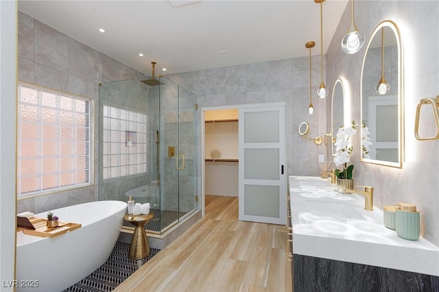 81 Alerion St, Las Vegas, NV 89138 - bathroom featuring a shower stall, wood finished floors, double vanity, a soaking tub, and tile walls