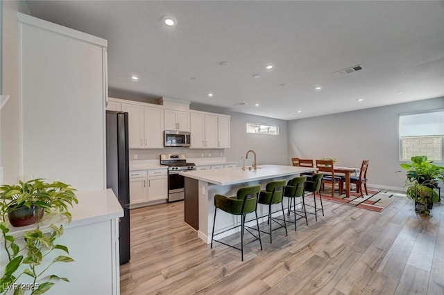 2651 Deep Canyon St, Henderson, NV 89044 - kitchen featuring appliances with stainless steel finishes, light wood-type flooring, a breakfast bar area, light countertops, and recessed lighting