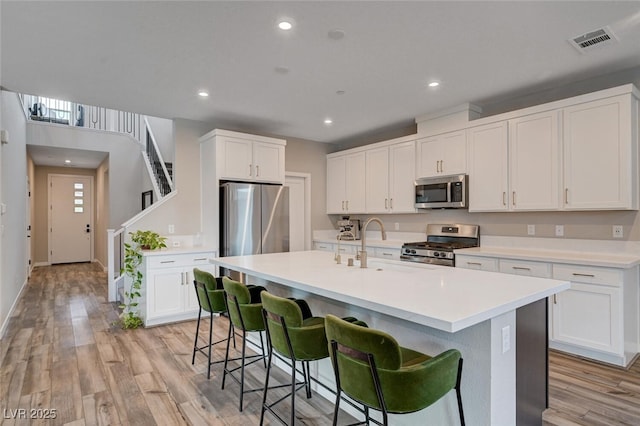2651 Deep Canyon St, Henderson, NV 89044 - kitchen featuring appliances with stainless steel finishes, a kitchen breakfast bar, light countertops, light wood-style floors, and an island with sink