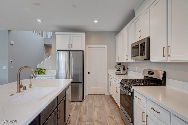 2651 Deep Canyon St, Henderson, NV 89044 - kitchen featuring appliances with stainless steel finishes, light wood-style floors, white cabinetry, recessed lighting, and light stone counters