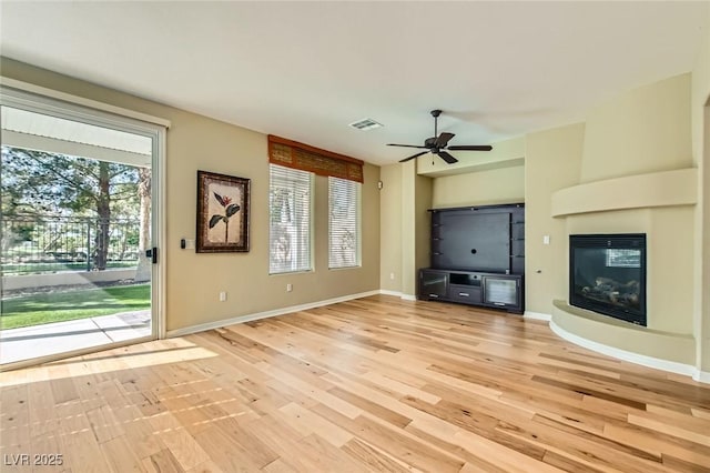 62 Myrtle Springs Ct, Las Vegas, NV 89148 - unfurnished living room with light wood finished floors, a glass covered fireplace, a ceiling fan, and baseboards