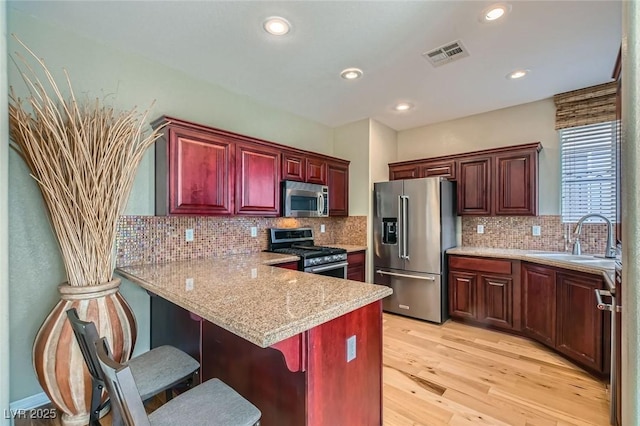 62 Myrtle Springs Ct, Las Vegas, NV 89148 - kitchen with stainless steel appliances, light wood-style floors, tasteful backsplash, a peninsula, and a kitchen breakfast bar