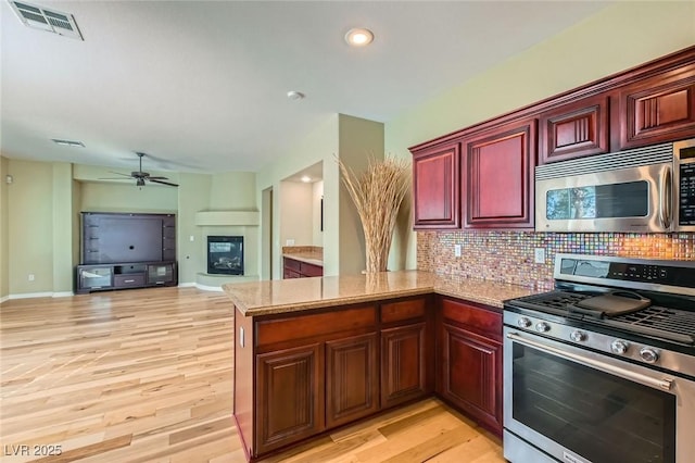 62 Myrtle Springs Ct, Las Vegas, NV 89148 - kitchen featuring stainless steel appliances, a peninsula, reddish brown cabinets, backsplash, and ceiling fan