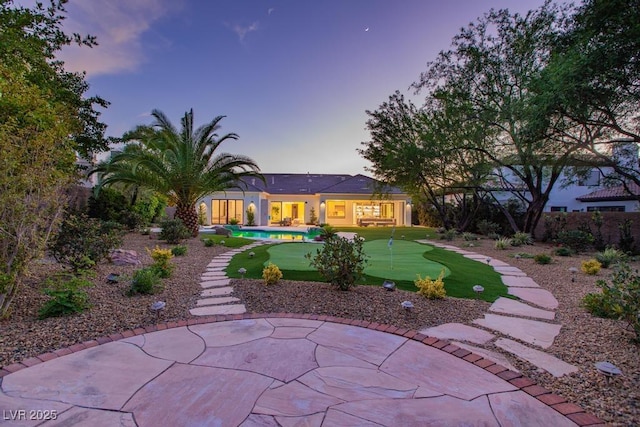 11926 Port Labelle Dr, Las Vegas, NV 89141 - back of house at dusk featuring a putting green and a patio area