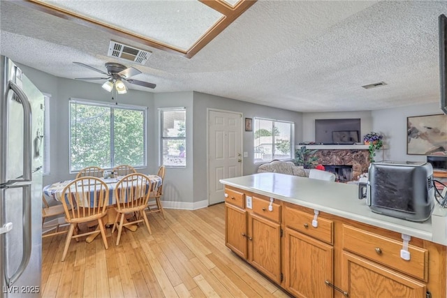7961 Lions Rock Way Unit 202, Las Vegas, NV 89128 - kitchen featuring a fireplace, light countertops, light wood finished floors, baseboards, and open floor plan