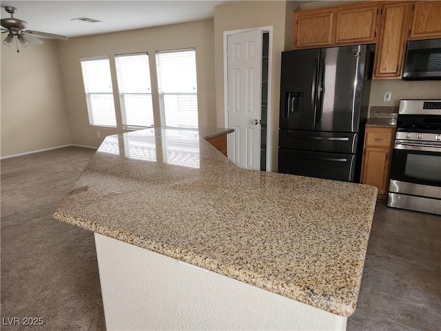 5052 Whistling Acres Ave, Las Vegas, NV 89131 - kitchen featuring black appliances, ceiling fan, light stone counters, open floor plan, and brown cabinetry