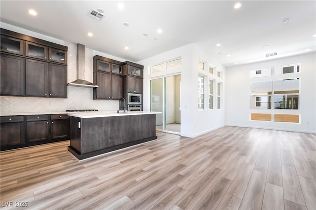 2501 Indigo Mountain St, Henderson, NV 89044 - kitchen with wall chimney exhaust hood, open floor plan, appliances with stainless steel finishes, light countertops, and an island with sink