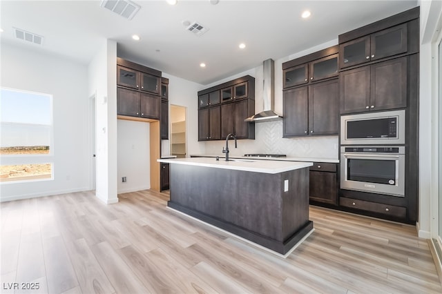2501 Indigo Mountain St, Henderson, NV 89044 - kitchen featuring wall chimney exhaust hood, appliances with stainless steel finishes, light countertops, backsplash, and light wood finished floors