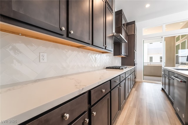 2501 Indigo Mountain St, Henderson, NV 89044 - kitchen with appliances with stainless steel finishes, a sink, backsplash, dark brown cabinets, and light wood-style flooring