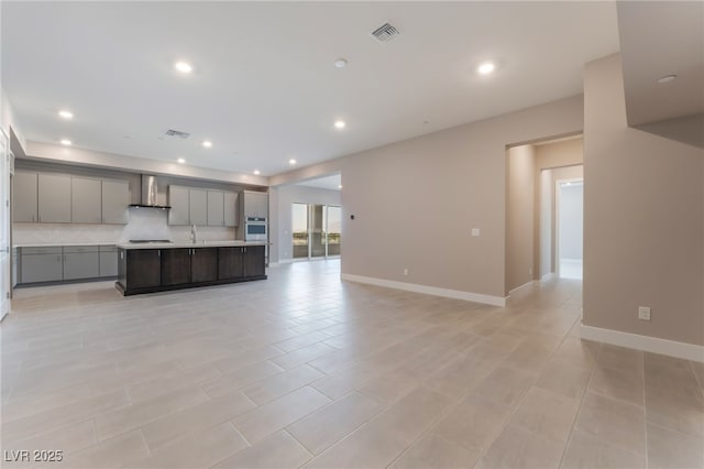 128 Los Cabos Dr Unit 301, Las Vegas, NV 89144 - kitchen with gray cabinetry, oven, wall chimney range hood, light countertops, and a center island with sink