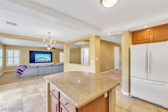 6558 Musette Ave, Las Vegas, NV 89139 - kitchen with freestanding refrigerator, a center island, light stone countertops, light tile patterned floors, and recessed lighting