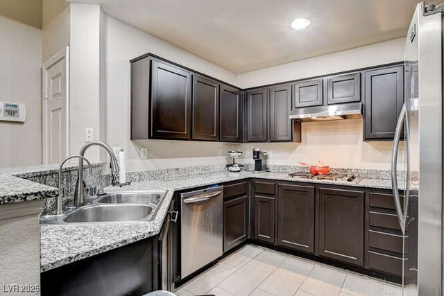 83 E Agate Ave Unit 207, Las Vegas, NV 89123 - kitchen with appliances with stainless steel finishes, under cabinet range hood, light tile patterned flooring, light stone countertops, and dark brown cabinetry