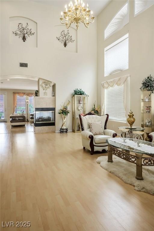 404 Via Sonador, Henderson, NV 89012 - living area featuring a towering ceiling, a chandelier, wood finished floors, and a tiled fireplace
