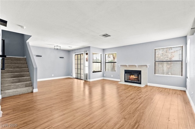 2062 Club Crest Way, Henderson, NV 89014 - unfurnished living room featuring baseboards, a fireplace with flush hearth, stairway, light wood-style floors, and a textured ceiling