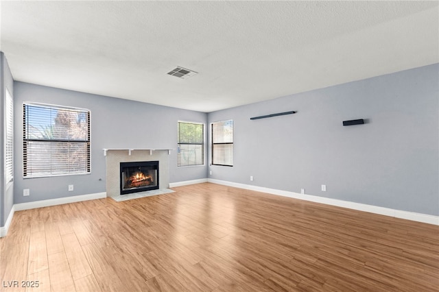 2062 Club Crest Way, Henderson, NV 89014 - unfurnished living room with light wood-style flooring, a fireplace with flush hearth, baseboards, and a textured ceiling