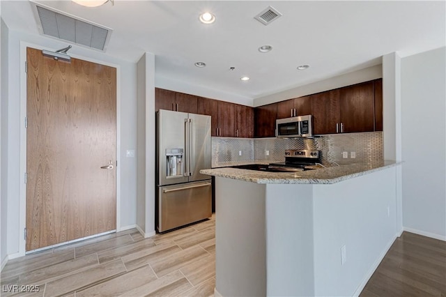 8255 S Las Vegas Blvd Unit 1816, Las Vegas, NV 89123 - kitchen featuring appliances with stainless steel finishes, light wood-style flooring, light stone countertops, dark brown cabinetry, and tasteful backsplash