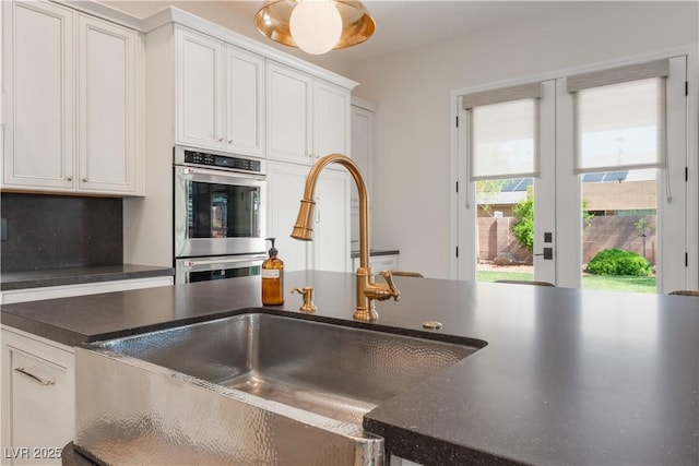 8504 Mystic Night Ave, Las Vegas, NV 89143 - kitchen featuring a sink, dark countertops, white cabinets, and stainless steel double oven