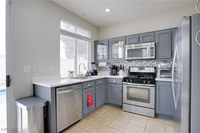 10605 Moon Flower Arbor Pl, Las Vegas, NV 89144 - kitchen with appliances with stainless steel finishes, gray cabinetry, a sink, light tile patterned floors, and light countertops