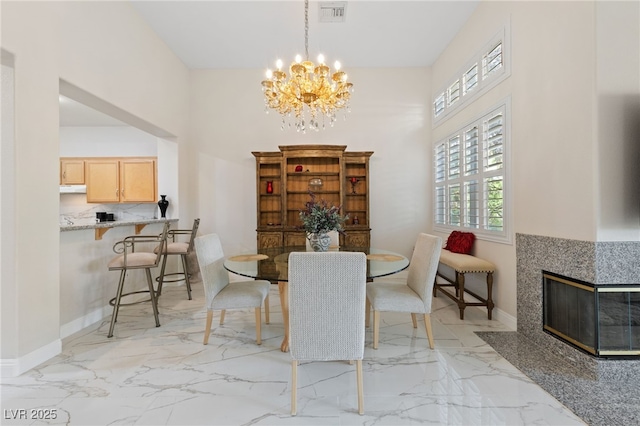 1912 Summer Pine Ct Unit 102, Las Vegas, NV 89134 - dining space featuring light marble finish flooring, a chandelier, baseboards, a towering ceiling, and a tiled fireplace