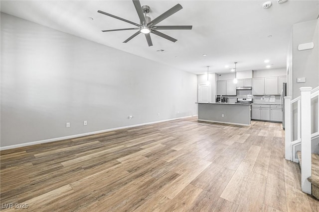3188 Via Da Vinci, Henderson, NV 89044 - unfurnished living room featuring light wood finished floors, ceiling fan, stairs, a sink, and recessed lighting