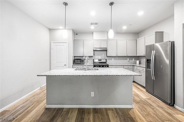 3188 Via Da Vinci, Henderson, NV 89044 - kitchen with stainless steel appliances, under cabinet range hood, a sink, light stone counters, and light wood finished floors