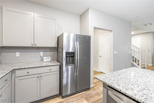 3188 Via Da Vinci, Henderson, NV 89044 - kitchen featuring stainless steel appliances, light wood finished floors, backsplash, light stone counters, and gray cabinetry